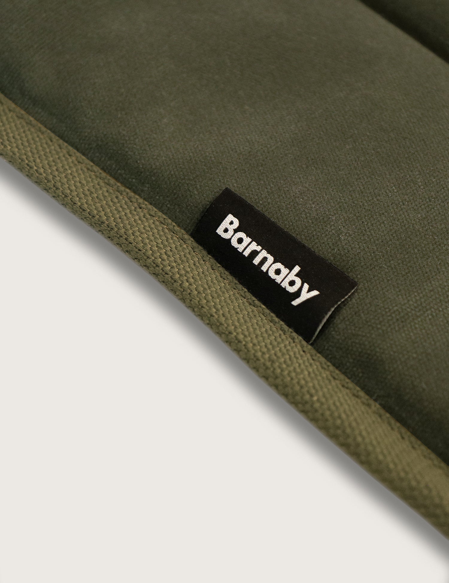 Close-up of a green cushion with a Barnaby label on a white background