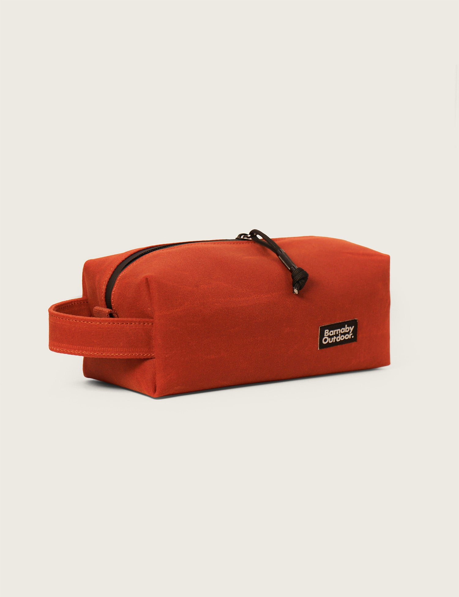 Orange toiletry bag with a black zipper on a beige background