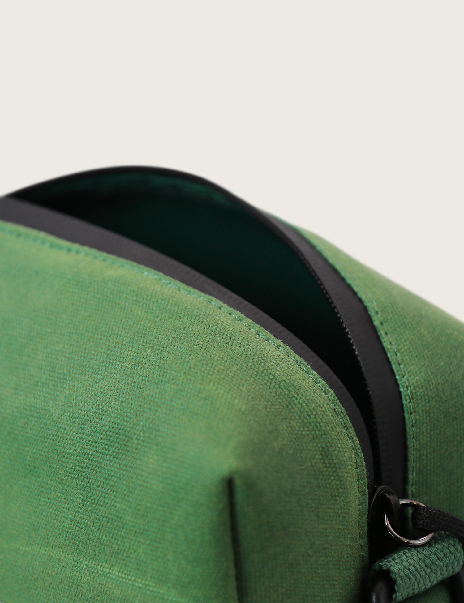 Green bag with a black zipper on a light gray background