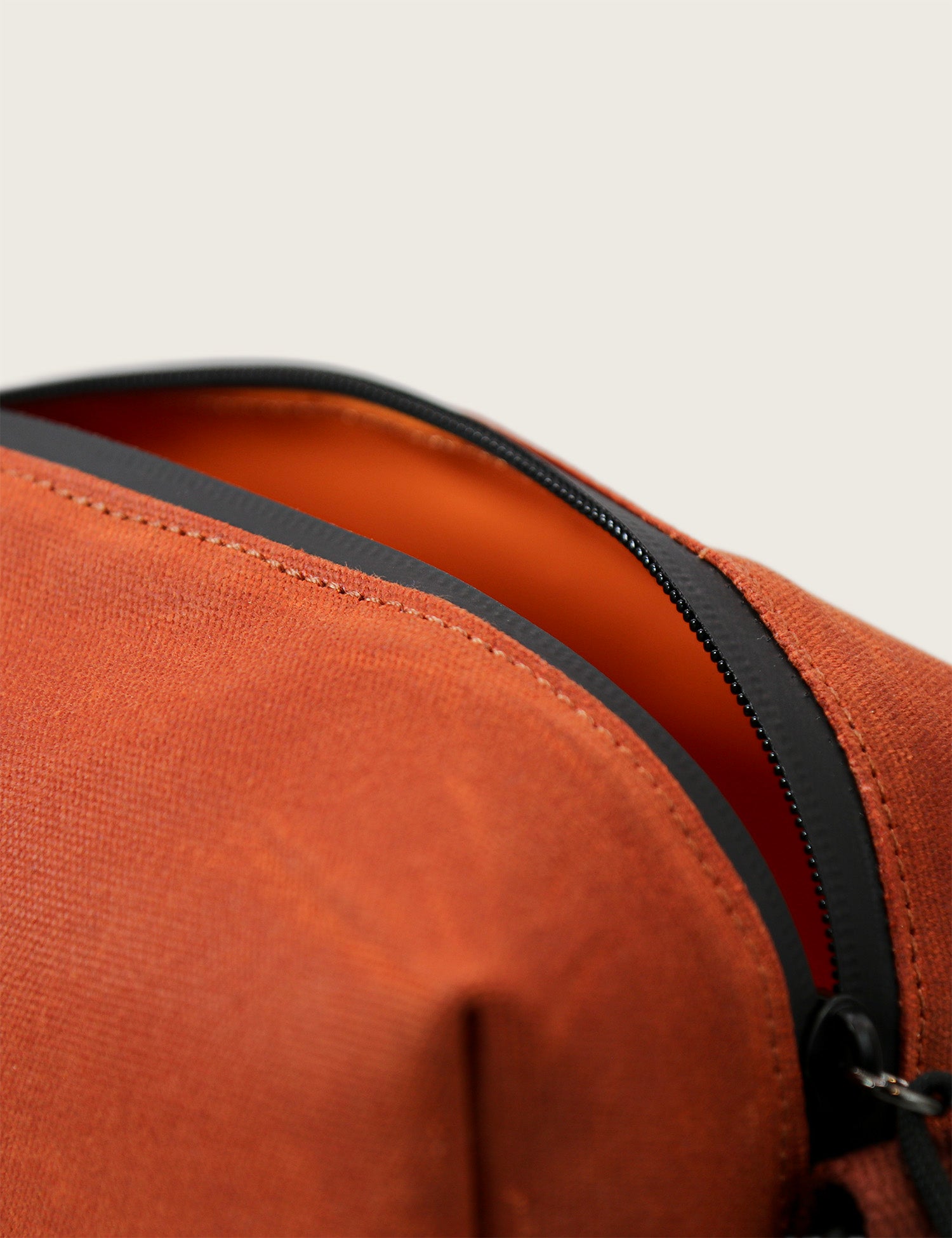 Close-up of a brown bag with a black zipper on a beige background