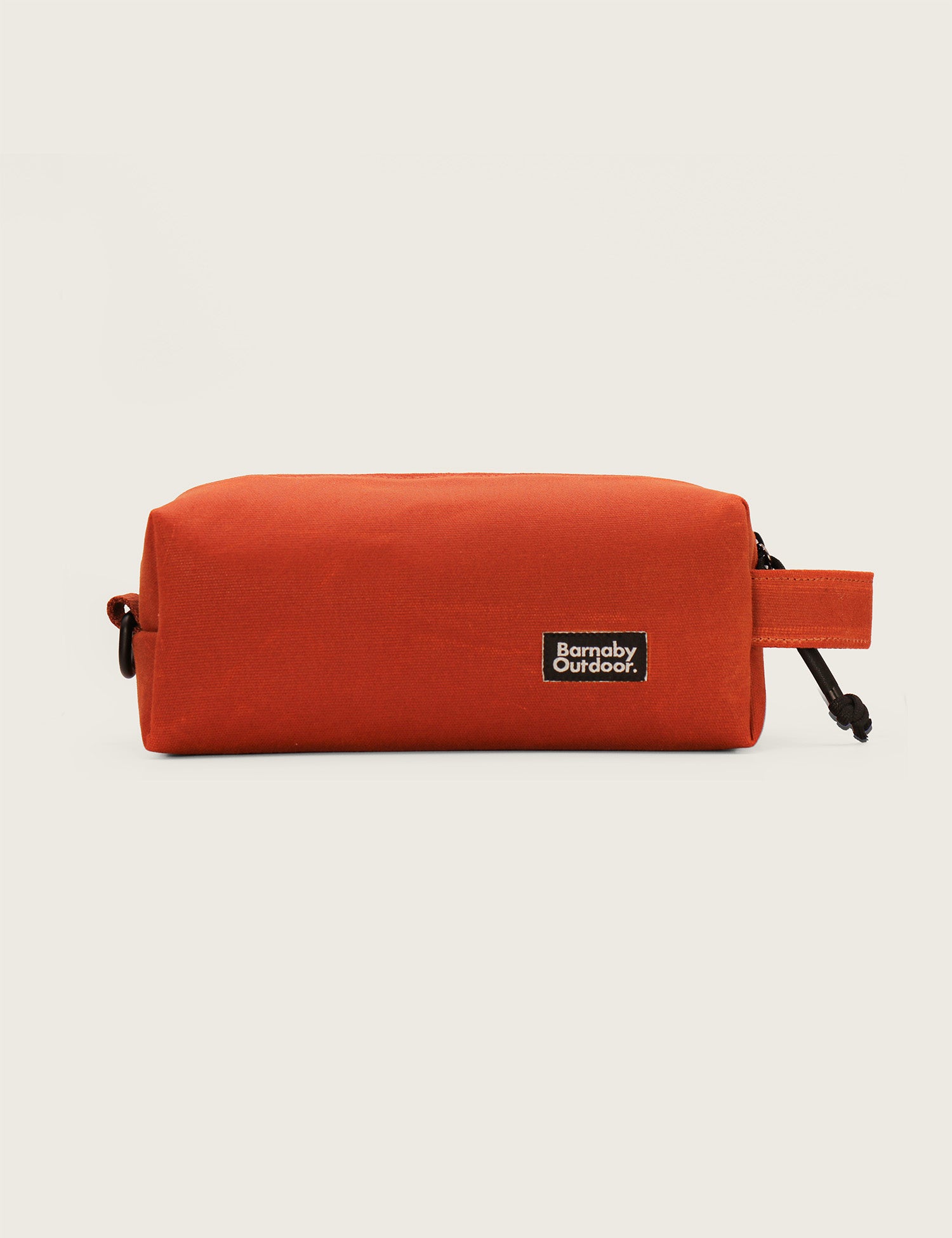Orange toiletry bag with a visible brand label on a light beige background