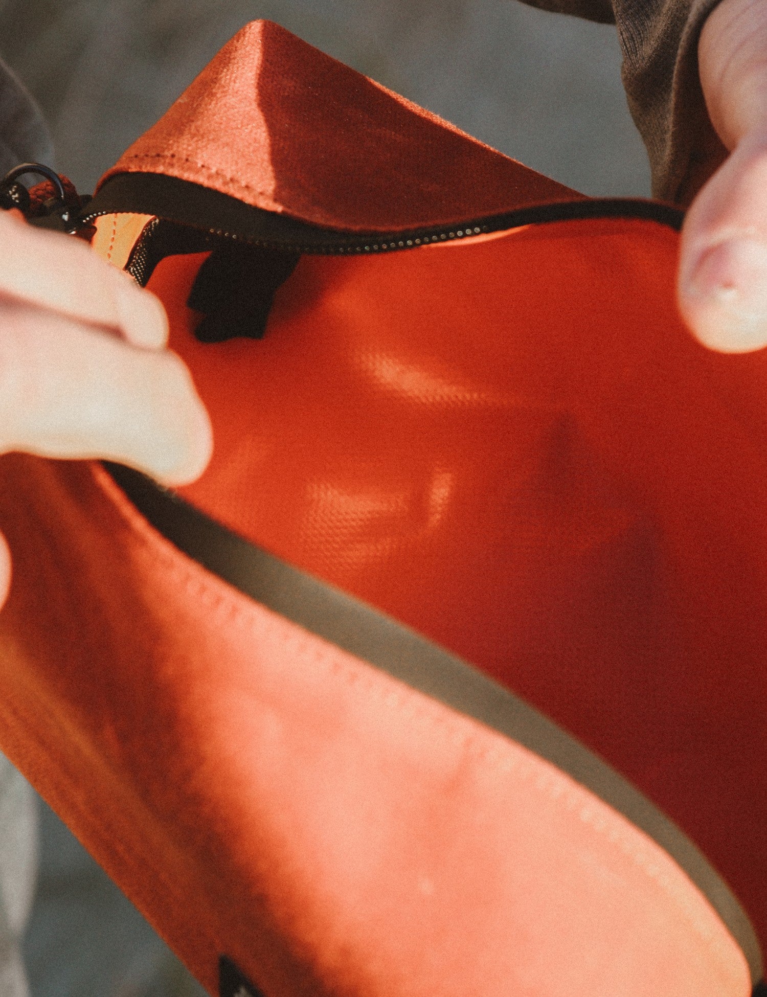 Close-up of a person holding an orange bag with a zipper.