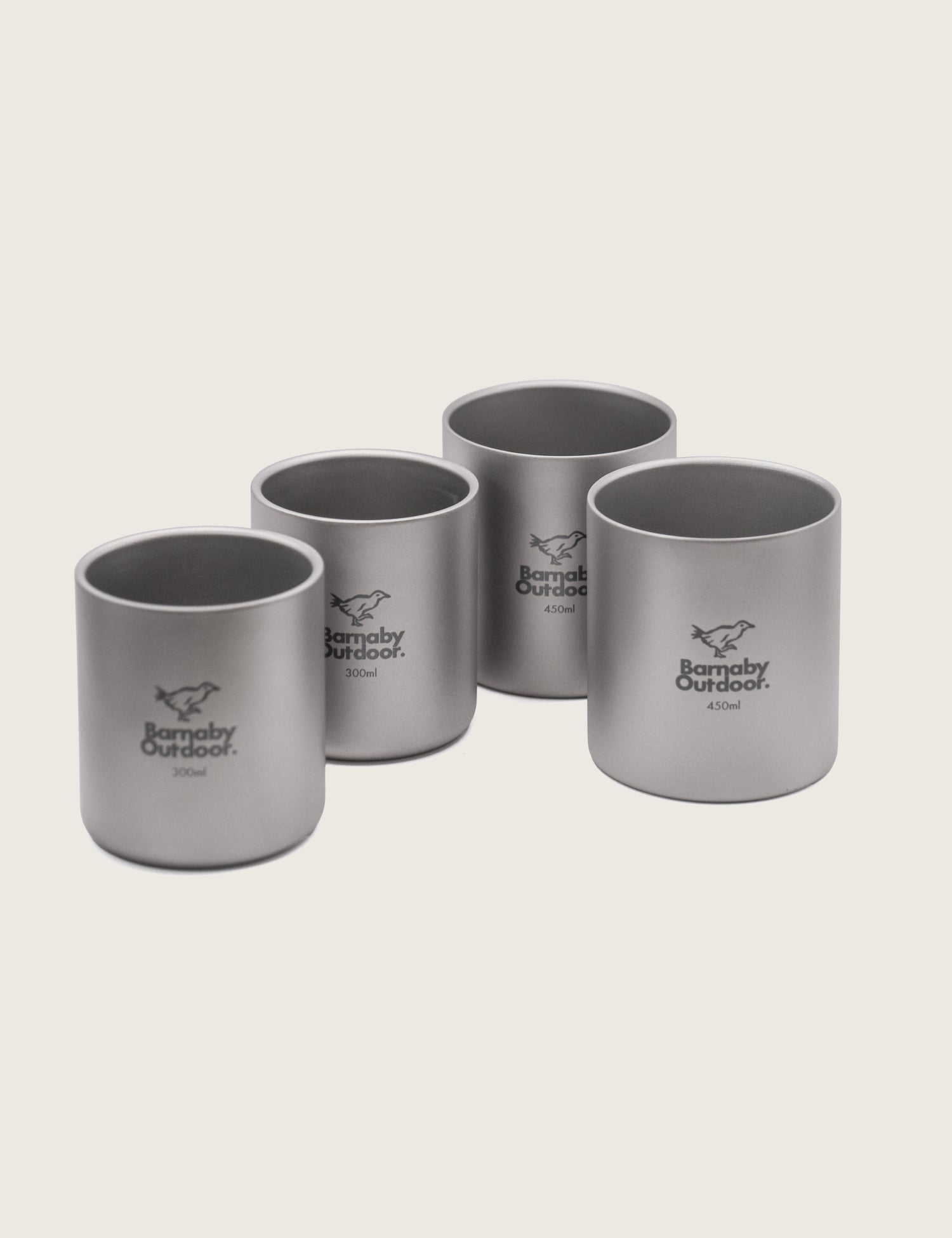 A set of four titanium mugs with double-wall insulation, stacked in a nesting fashion. Each mug has a capacity label and a laser etching of a bear on the front.