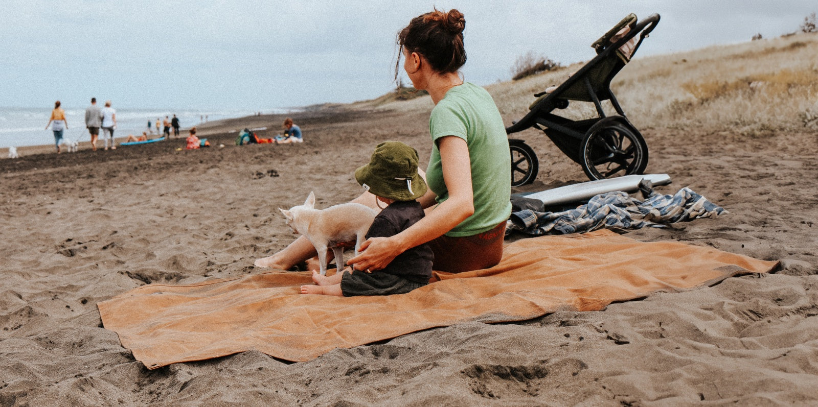 Woman with child and dog on a beach waxed canvas blanket at the beach